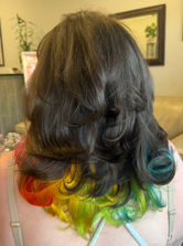 Back view of dark brown wavy hair with a vivid rainbow ombré underneath