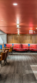 Modern restaurant and bar with red ceiling, green and red leather seating, wooden furniture, and ambient lighting — elegant hospitality interior design. Captured by Strata Visuals.
