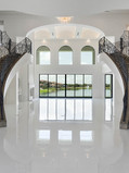 Grand foyer with dual curved staircases, chandelier, and lake view, photographed for MLS real estate listing in Houston.