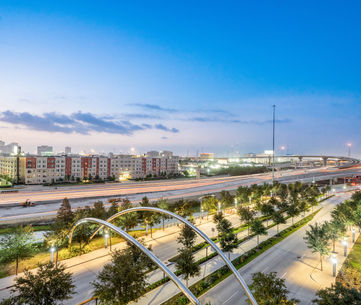 Captivating twilight shot capturing an illuminated city skyline with flowing highway light trails and modern architecture under a deep blue dusk sky. A perfect display of professional twilight cityscape and real estate photography. Captured by Strata Visuals.