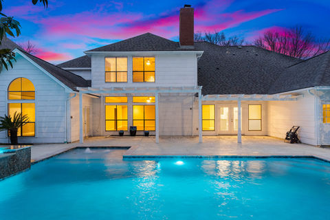 Captivating twilight photo of a modern home with a glowing pool under a vibrant pink and blue sky. Perfect dusk lighting enhances exterior warmth and architectural detail. Captured by Strata Visuals.
