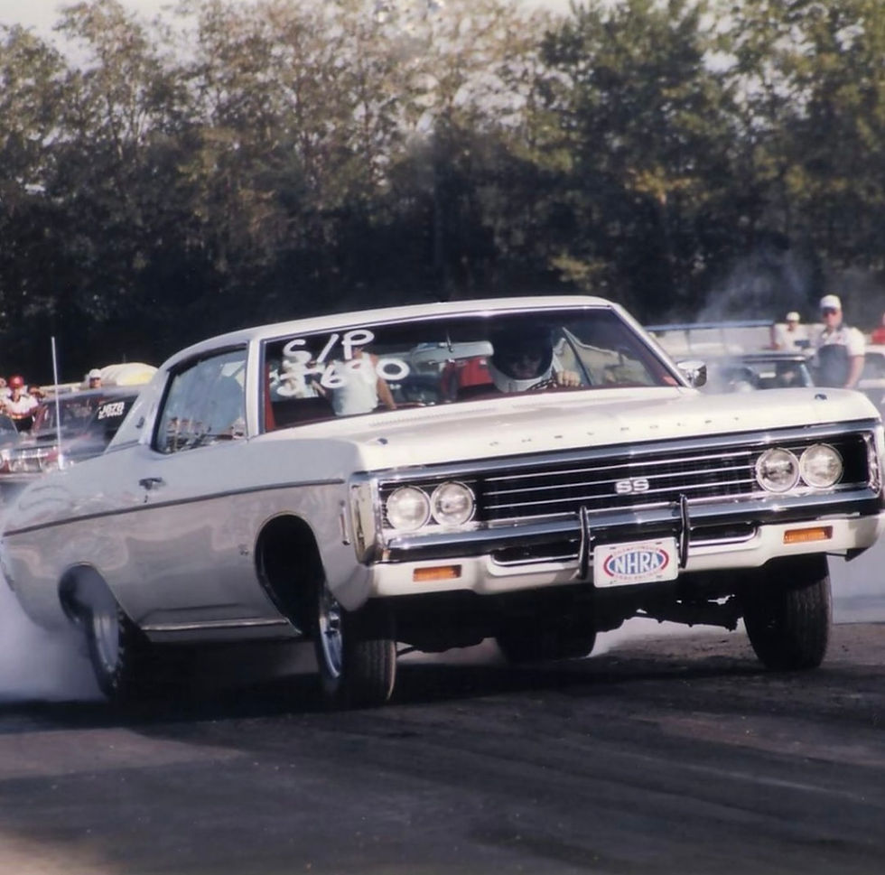 A vintage white muscle car with an NHRA license plate performing a burnout at a drag racing event, demonstrating the power and performance of Custom Touch Auto Body's restoration work.