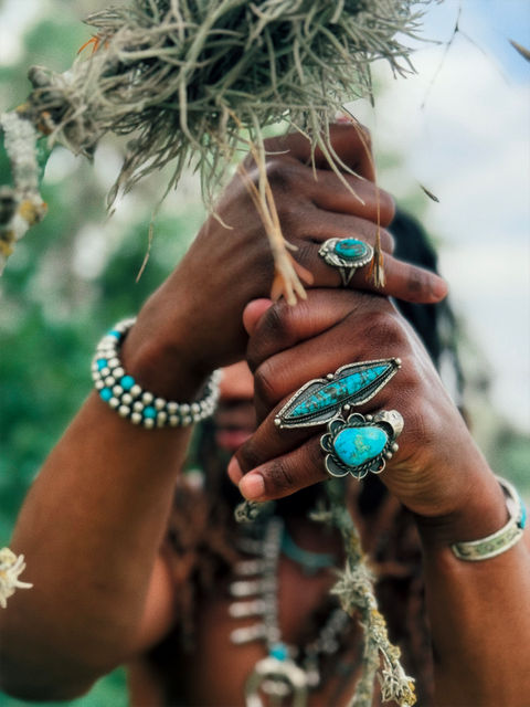 Zakan shows off Native American collection. Model Zakan outdoors and shirtless with Native American rings, bracelets, and statement necklaces.