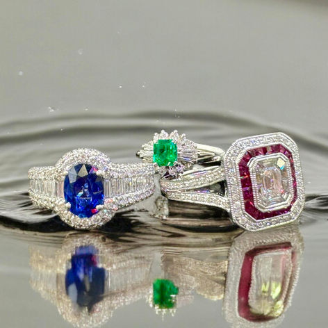 Ruby, sapphire, emerald & diamond vintage & art-deco rings on rippled water serface. Vintage fashion meets modern elegance with trendy white gold classic gemstone jewelry.