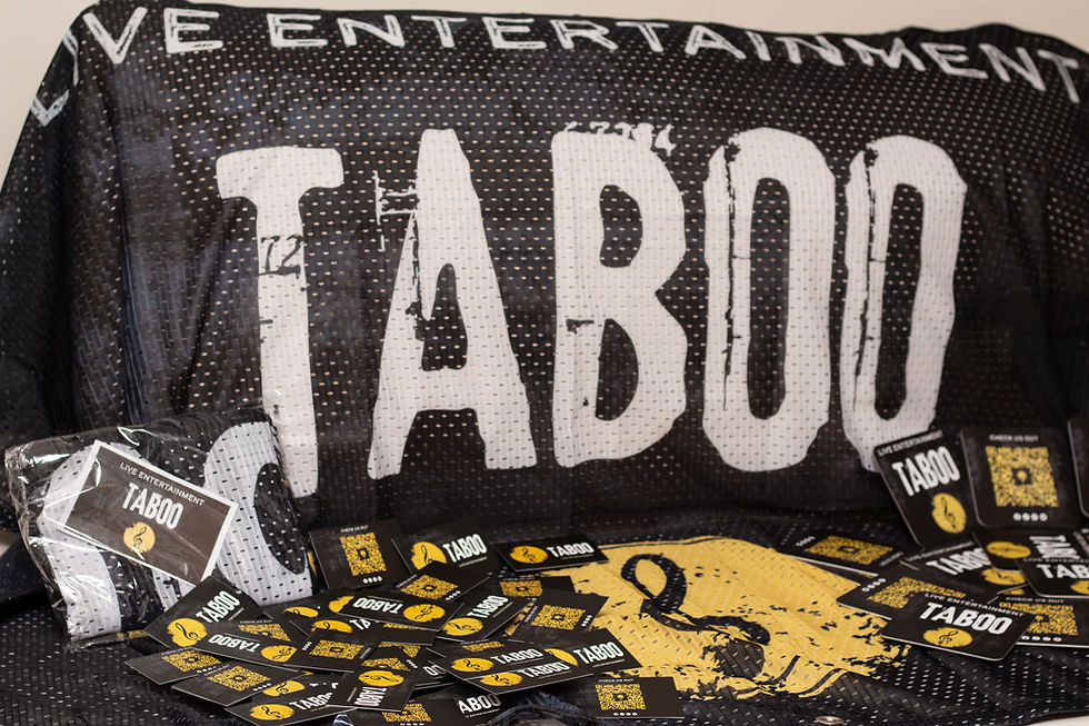 Black backdrop with large white "TABOO" text, numerous black and yellow cards scattered below, displaying the words "Live Entertainment."