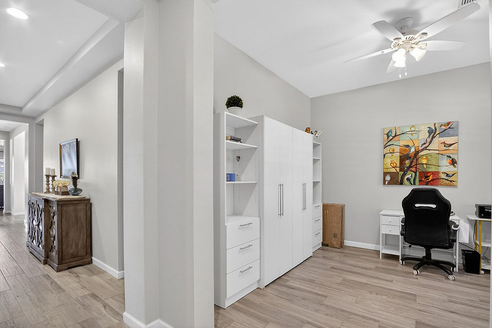 Room with murphy bed, desk, gaming chair, and hallway with TV