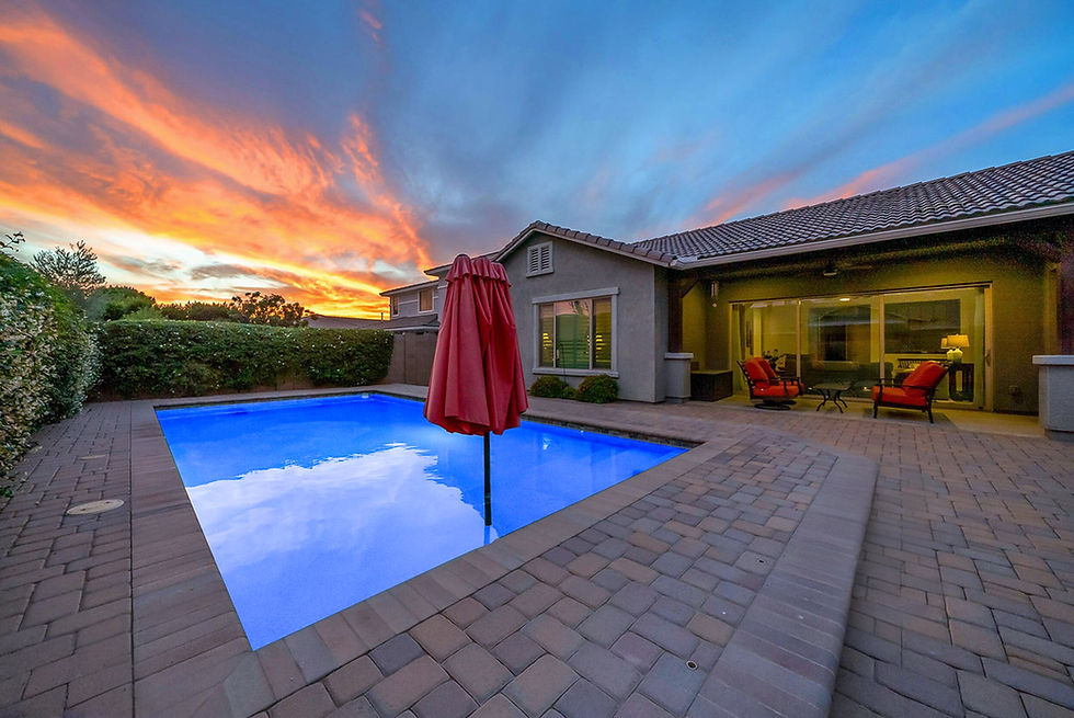 Backyard pool and house at twilight with colorful sky