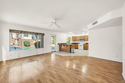 Spacious living room with hardwood floors, kitchen, and pool view