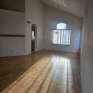 Empty room with wood floor, vaulted ceiling, and sunlit window