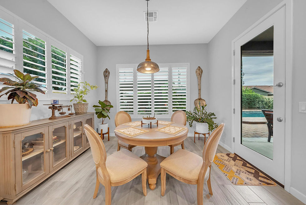 Bright dining area with round table, chairs, sideboard, and view to pool patio.