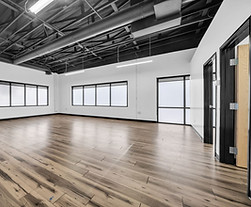 Empty commercial space with hardwood floors and large windows