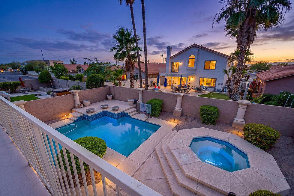 Twilight view of a real estate backyard with pool and hot tub