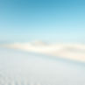 White sand dunes set against a light blue sky.jpg