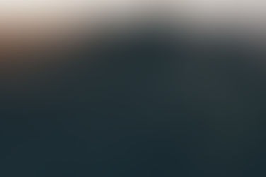 Spiderweb glistens with dew in a grassy field at sunrise. Warm light creates a serene, tranquil mood against a blurred background.