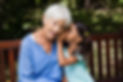 girl whispering into her grandmothers ear
