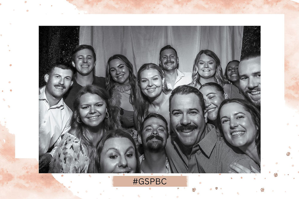 Large group posing in a black-and-white photo booth rental at a local event venue.