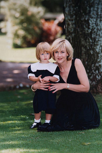 Woman kneeling with child on grass in formal attire for family portrait