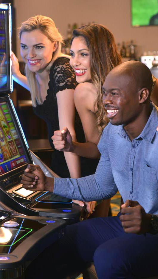 Man and two women celebrating at a gaming machine in a casino