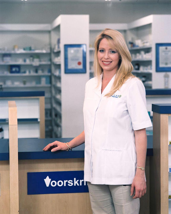Pharmacist in lab coat behind pharmacy counter