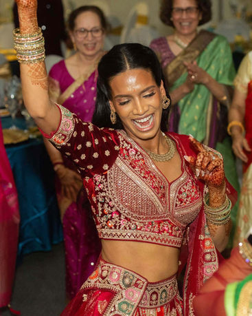 Joyful woman in red embroidered lehenga dancing at a party