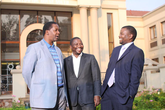 Three executives smiling in front of a corporate building