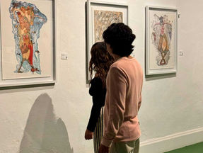 Couple with their backs to the camera looking at paintings