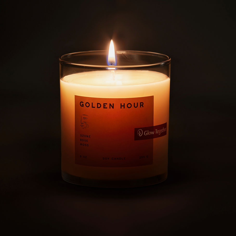 Lit Golden Hour candle glowing with a soft warm flame in a dark setting
