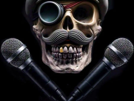 Skull with mustache and monocle wearing a flat cap, flanked by microphones — stylized symbol for Captain’s Blog entry announcing official launch