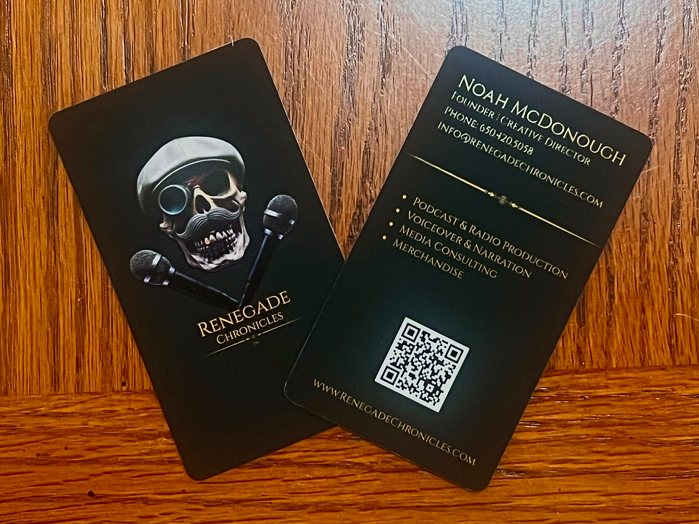 Two black business cards for Renegade Chronicles displayed on a wooden surface — one showing the skull-and-microphones logo with a monocle and cap, and the other showing contact info for Noah McDonough, including a QR code linking to the brand’s website.