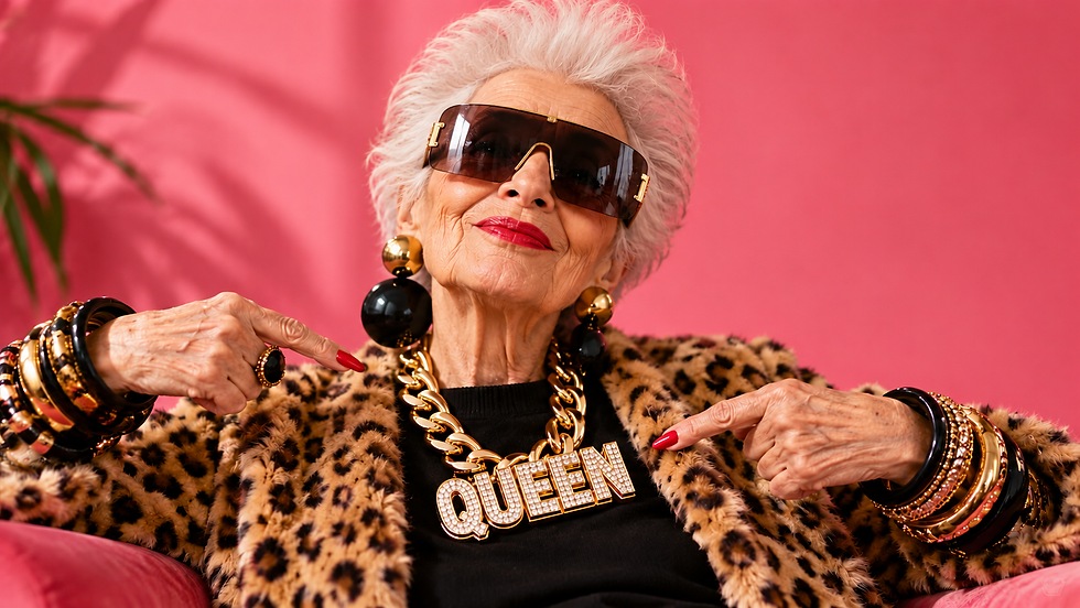 A woman in her 70s wearing a leopard-print fur jacket, large black and gold ball earrings, large black visor sunglasses, pointing to a thick gold chain with the word 'queen' on it.