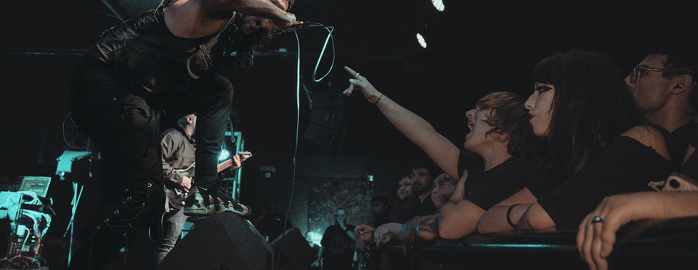 Renesans vocalist David Benites vocalizes at the front of the stage with a fan reaching out across the barricade while others look on at the WC Social Club in Chicago, IL