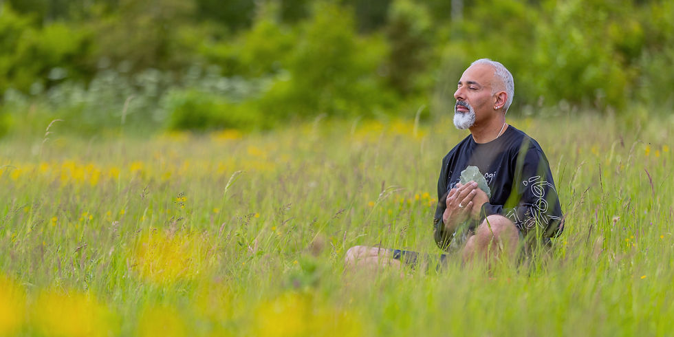 Virinder meditating with a crystal in a field