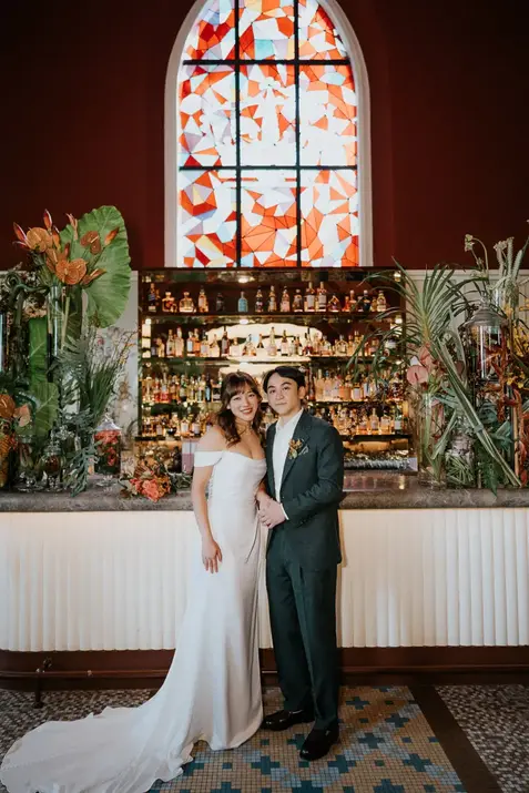Bride and groom standing in front of Claudine wedding bar