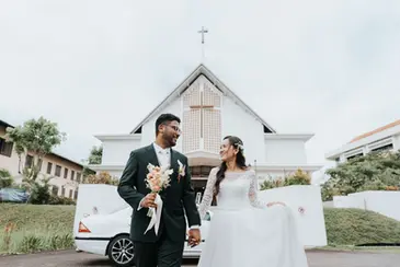 Bride and groom running towards camera outside Church of the Ascension Singapore before wedding ceremony.