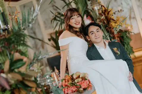Claudine in a white wedding gown posing with her groom.