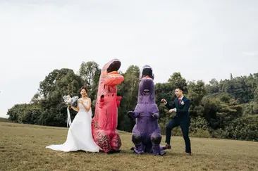 Bride and groom dancing with dinosaur mascots during bridal party photoshoot at Canterbury Road open field Singapore before The Westin Wedding banquet.