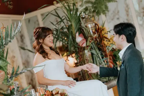 Bride Claudine smiling at her groom while holding hands.
