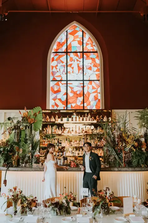 Bride and groom standing in front of a wedding bar with stained glass