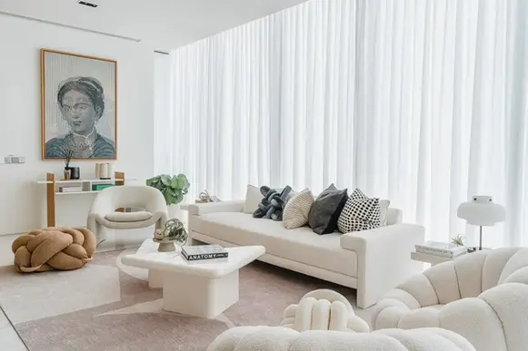 Bright open-plan living area featuring floor-to-ceiling windows and a soft neutral palette.