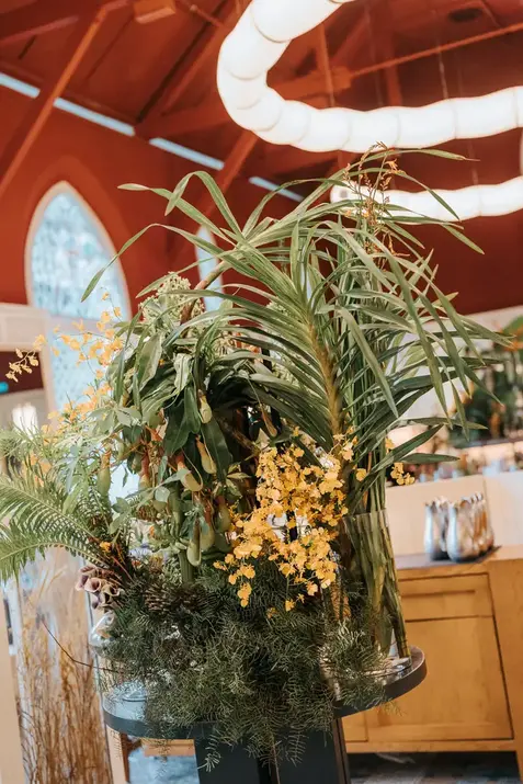 Tropical floral arrangement with yellow orchids and palms