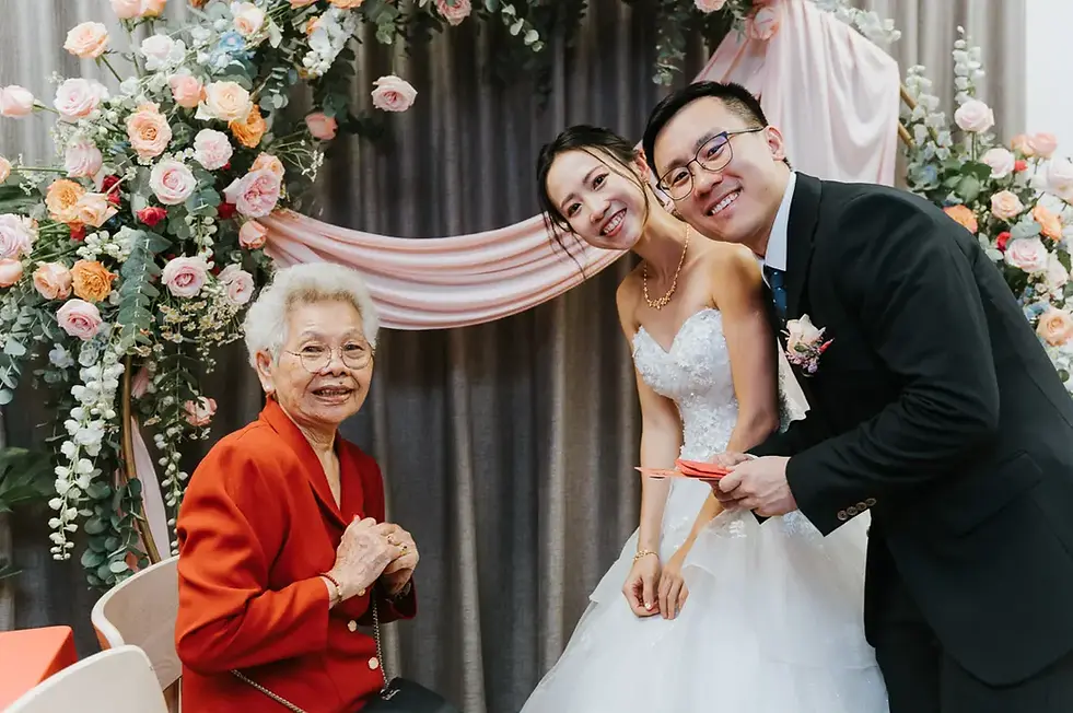 Bride and groom serving tea to grandmother during tea ceremony at Crossings Cafe Singapore.