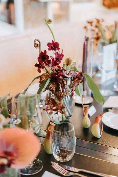 Burgundy orchids in a glass vase at Claudine wedding