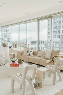Bright open-plan living room featuring floor-to-ceiling windows and a neutral colour palette.