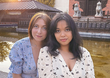 Zwei Frauen im Sommerkleid schauen bei Sonnenschein in die Kamera und lächeln