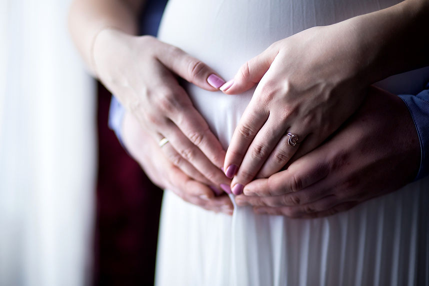 Photo de grossesse avec les mains des parents, sur le ventre de la mère, formant un coeur