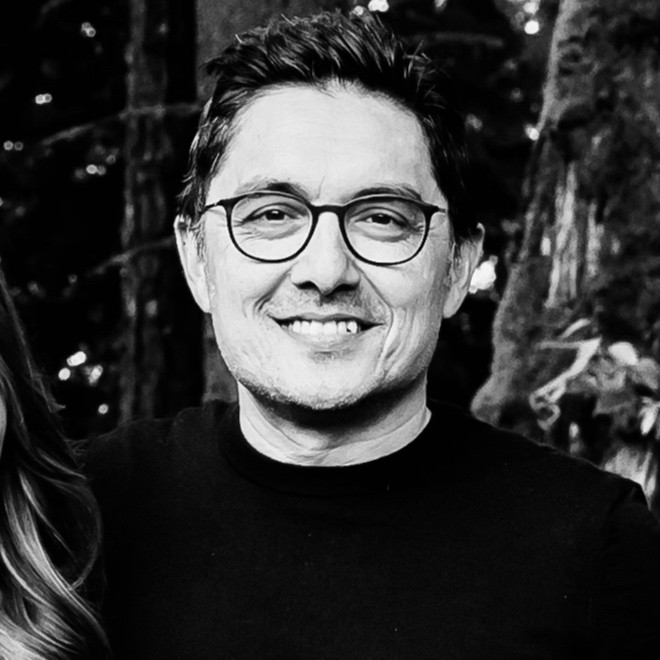 a smiling man with glasses shown in black and white