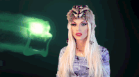 GIF of Katya in her raccoon hat with a evil green ghost flying behind her. Text for her name says, "Neve Campbell".