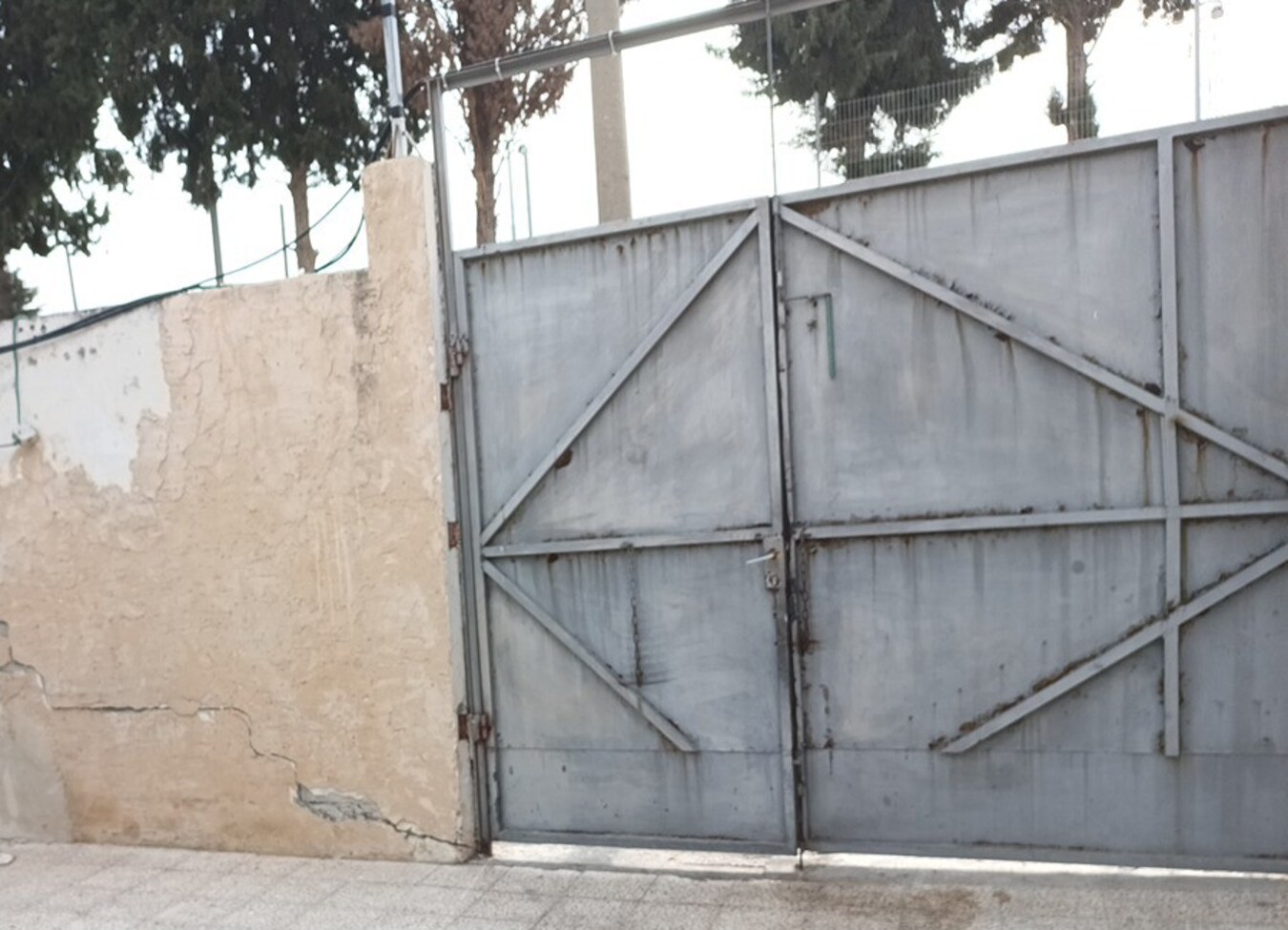 סדק מתמשך בקיר לצד שער מתכת לאחר פגיעת רכב
