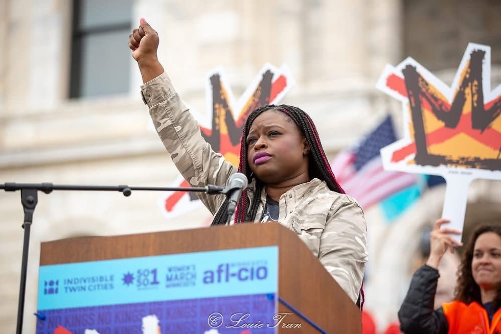 Nekima Levi Armstrong behind a podium with her fist in the air.