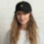 Woman wearing a black streetwear cap with a gold logo.